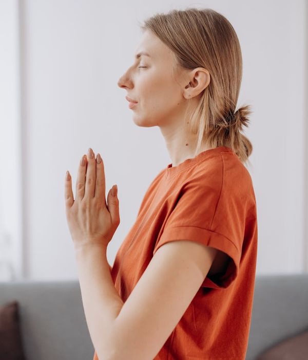 A calm woman practicing a gentle yoga pose in a bright, peaceful room.